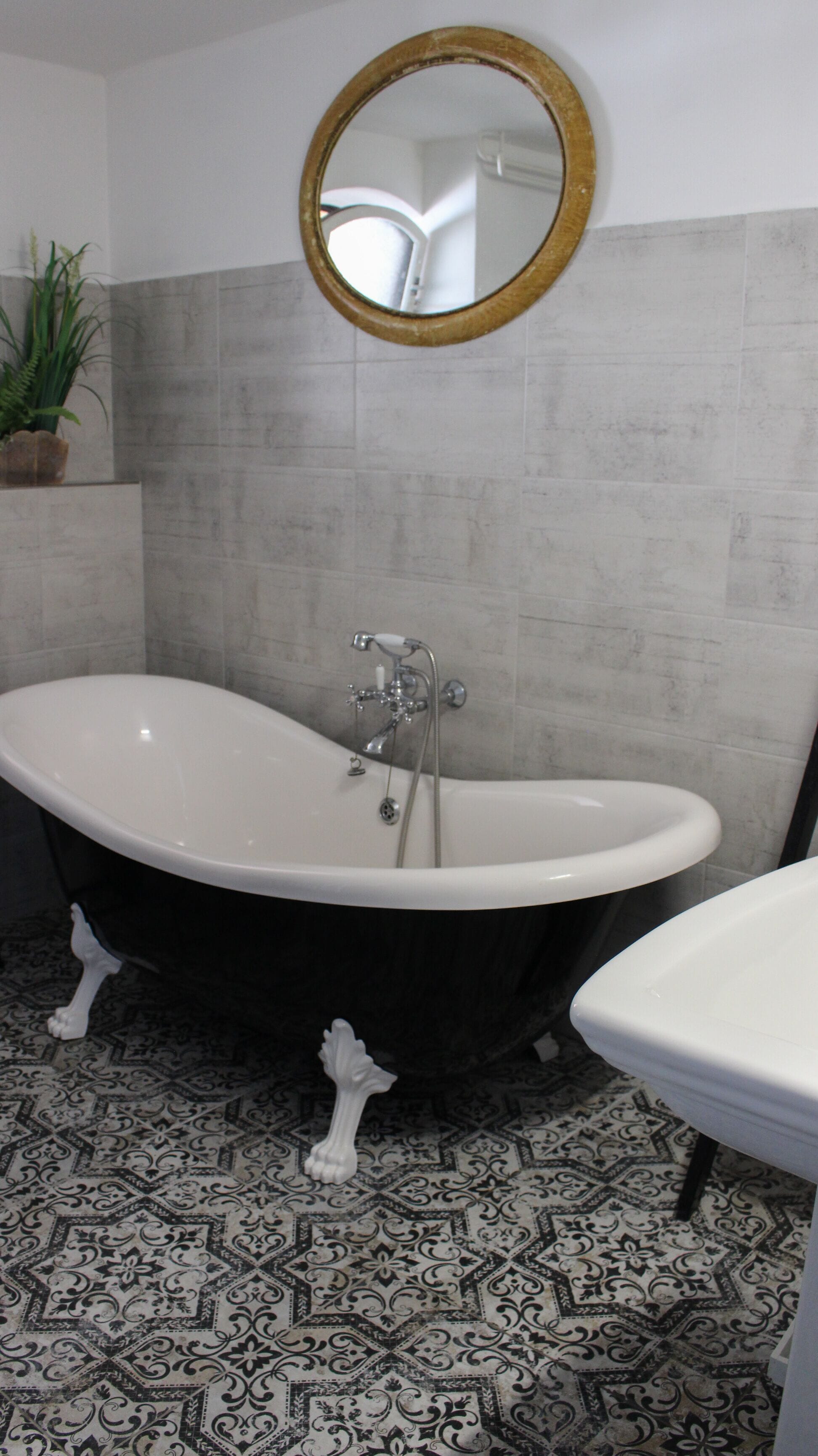 A bathroom with a freestanding bathtub, a sink, and a mirror on the wall.