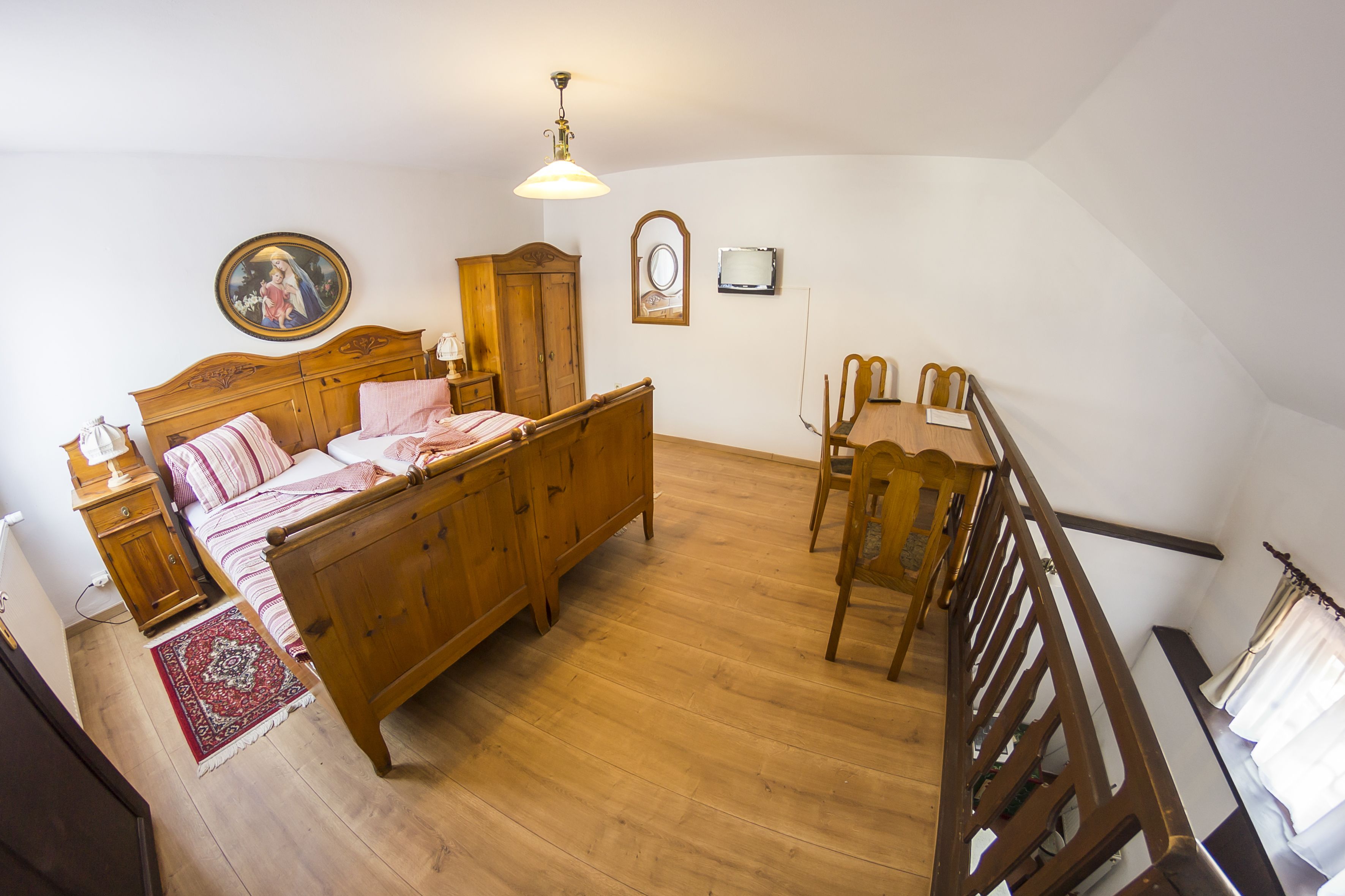 Un dormitorio con una cama de madera, una mesita de noche, un aparador, una silla de madera y una escalera.