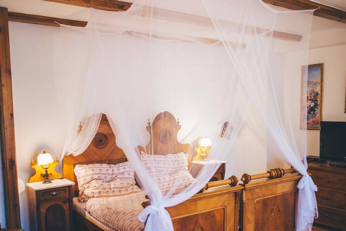A traditional wooden bed with a canopy, a bedside table with a lamp, and a rug on the floor.