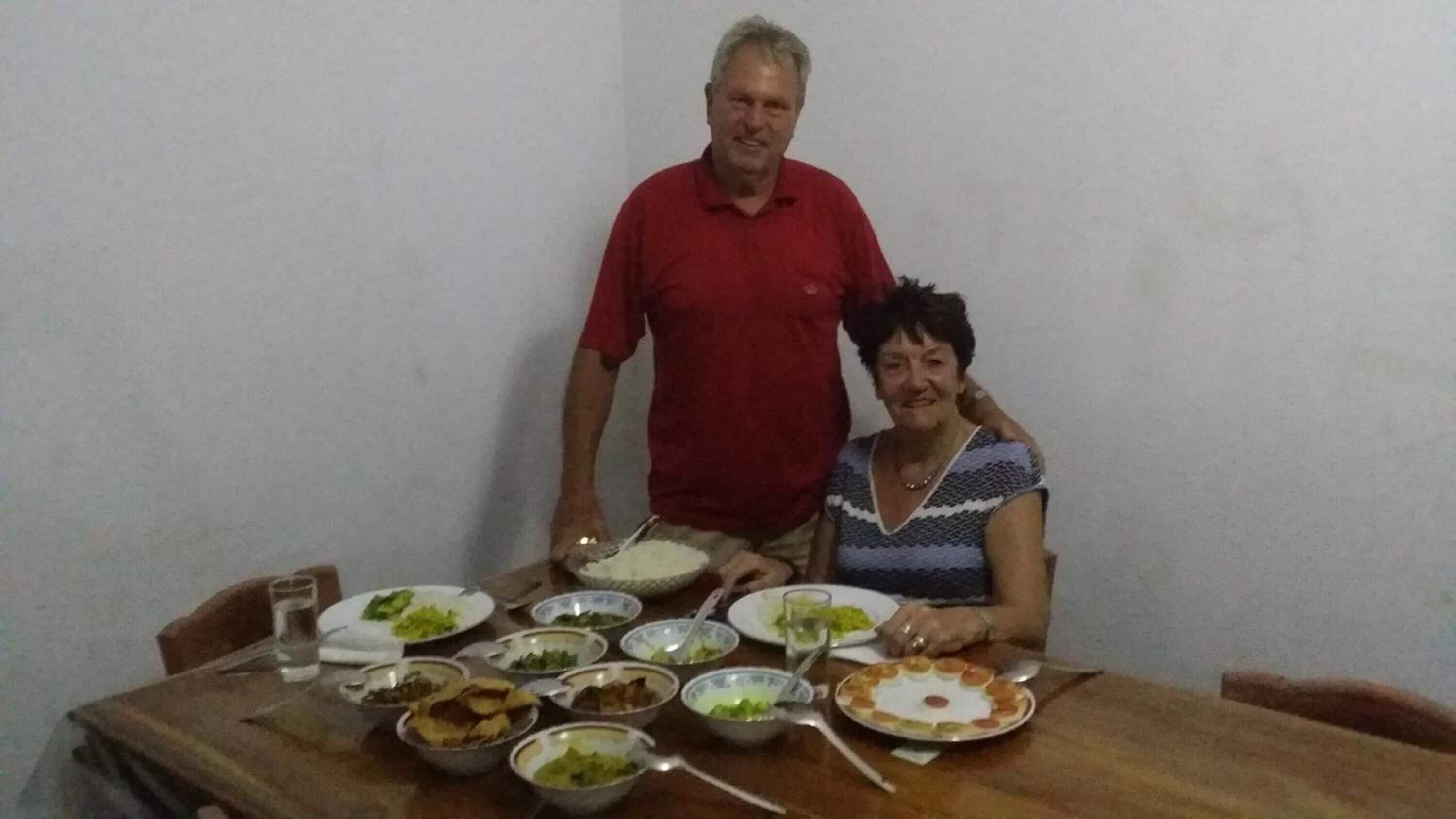 A dining table with various dishes and a man standing behind it.