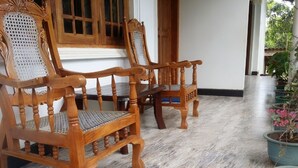 Deux chaises en bois ornées de sculptures complexes, un sol carrelé et des plantes en pot.