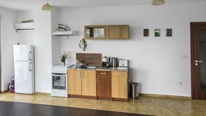 A modern kitchen with wooden cabinets, a built-in oven, a sink, and a coffee maker. There is a trash bin and a small potted plant on the counter. - Flora Apartment Centrum (Sofia)