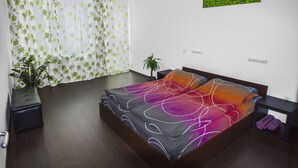 A bedroom with a bed, a potted plant, a nightstand, and a wall-mounted artwork. - Flora Apartment Centrum (Sofia)
