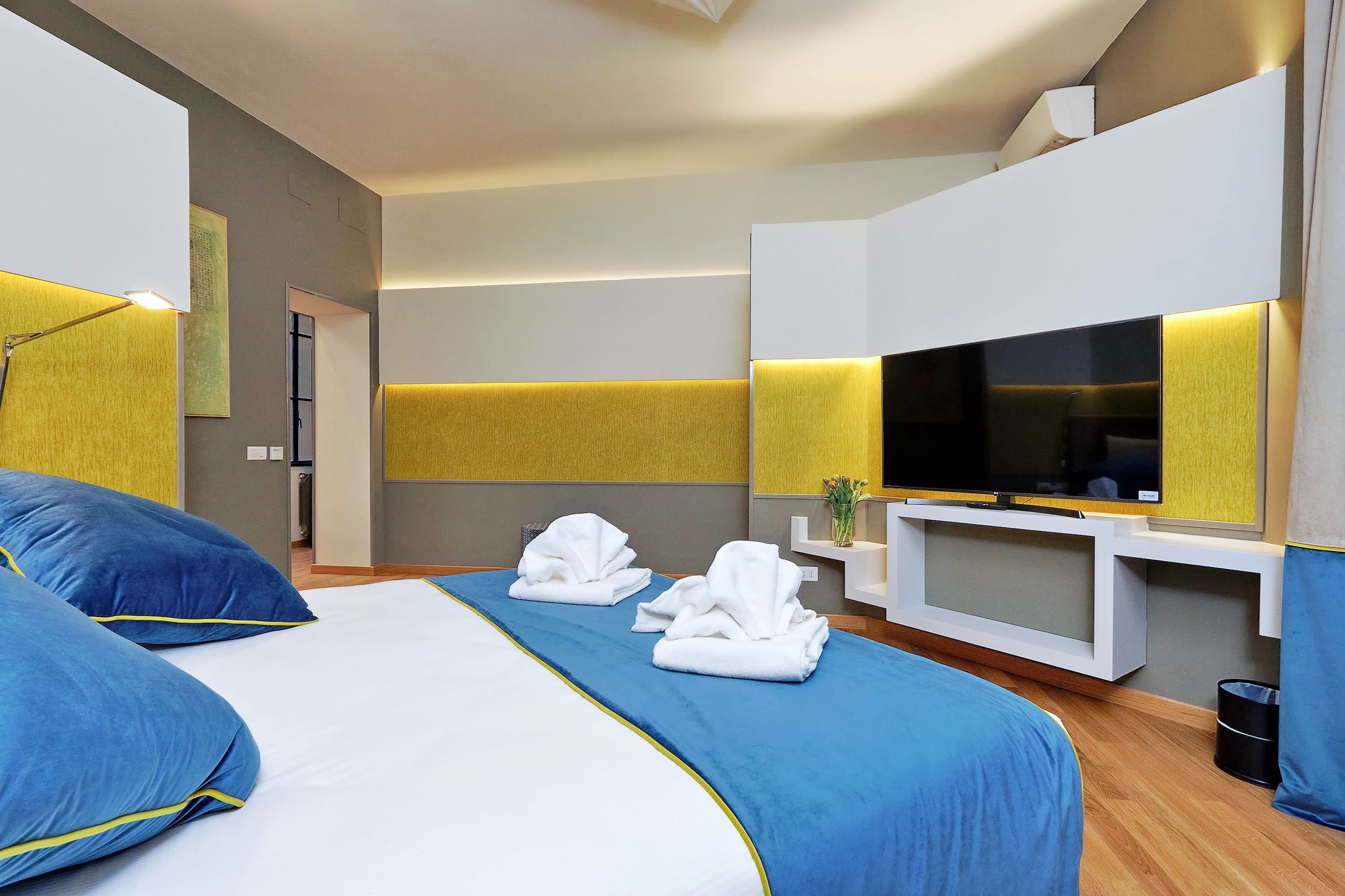A modern hotel room with a large bed, a flat-screen TV, and a minimalist design.