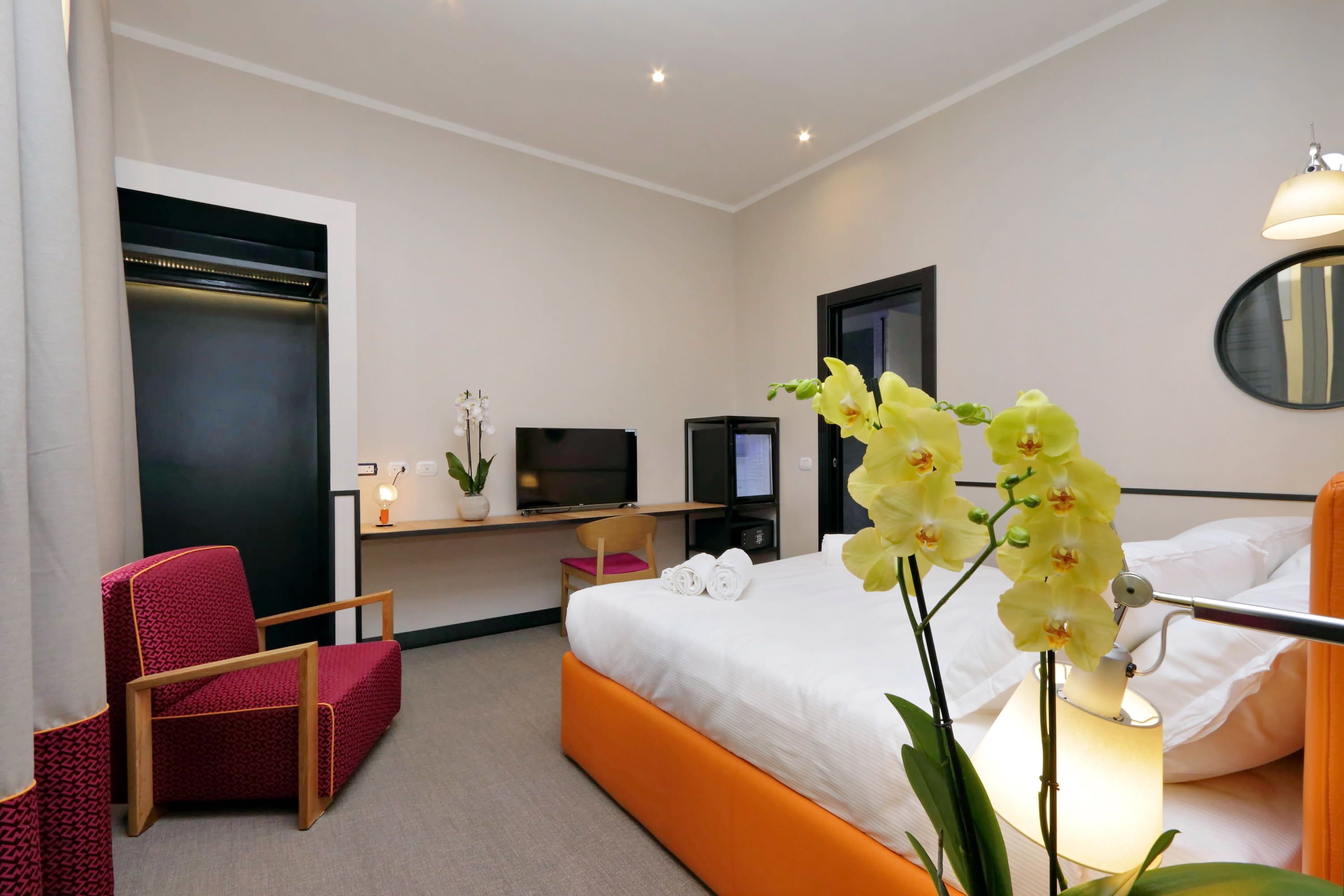 A hotel room with a bed, a desk with a computer, a chair, and a TV.