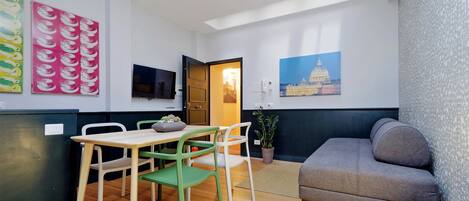 A compact living space with a dining area, a sofa, and a television.