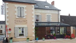 A hotel with a reception area, outdoor seating, and potted plants. - Au Bosquet Fleuri (Martizay)