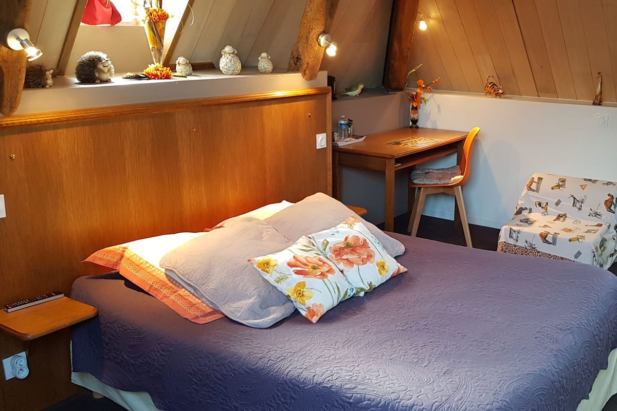 A bedroom with a bed, a desk, a chair, and a small table.