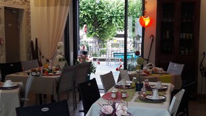 A dining area with tables set for breakfast, featuring a view of the outdoors through large windows. - Au Bosquet Fleuri (Martizay)