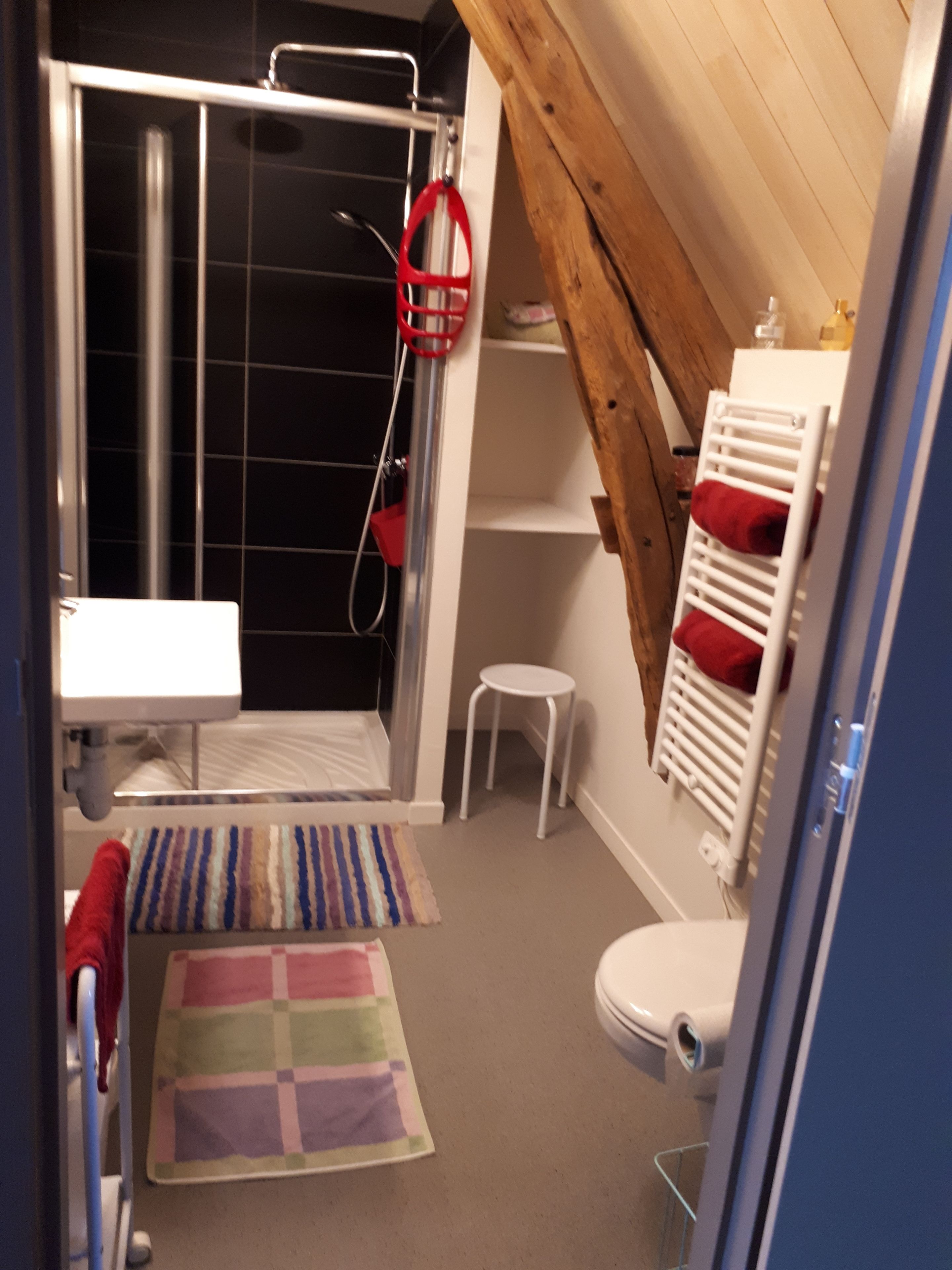 A small bathroom with a shower, a toilet, a sink, and a wooden ceiling.