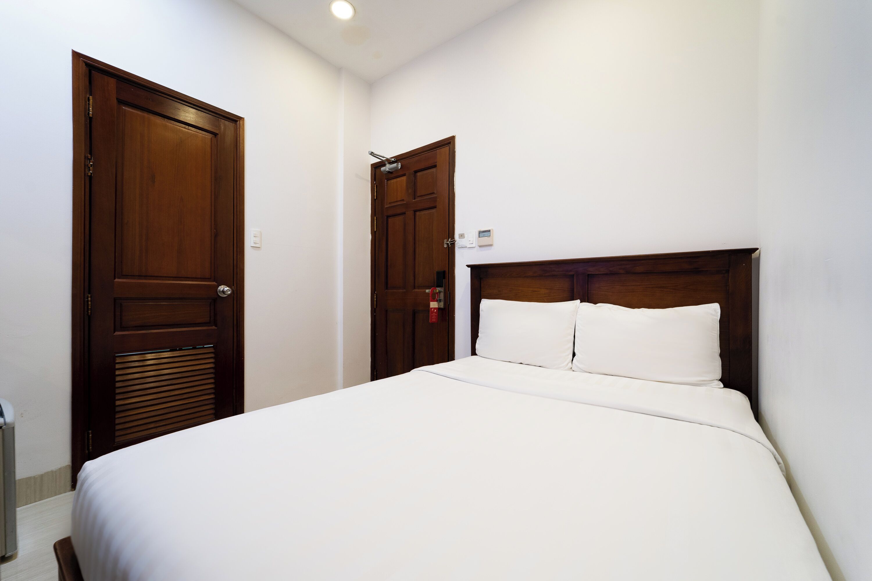 Una habitación de hotel con una cama grande, dos puertas de madera y una pared blanca.