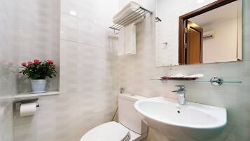 Een moderne badkamer met toilet, wastafel en spiegel.