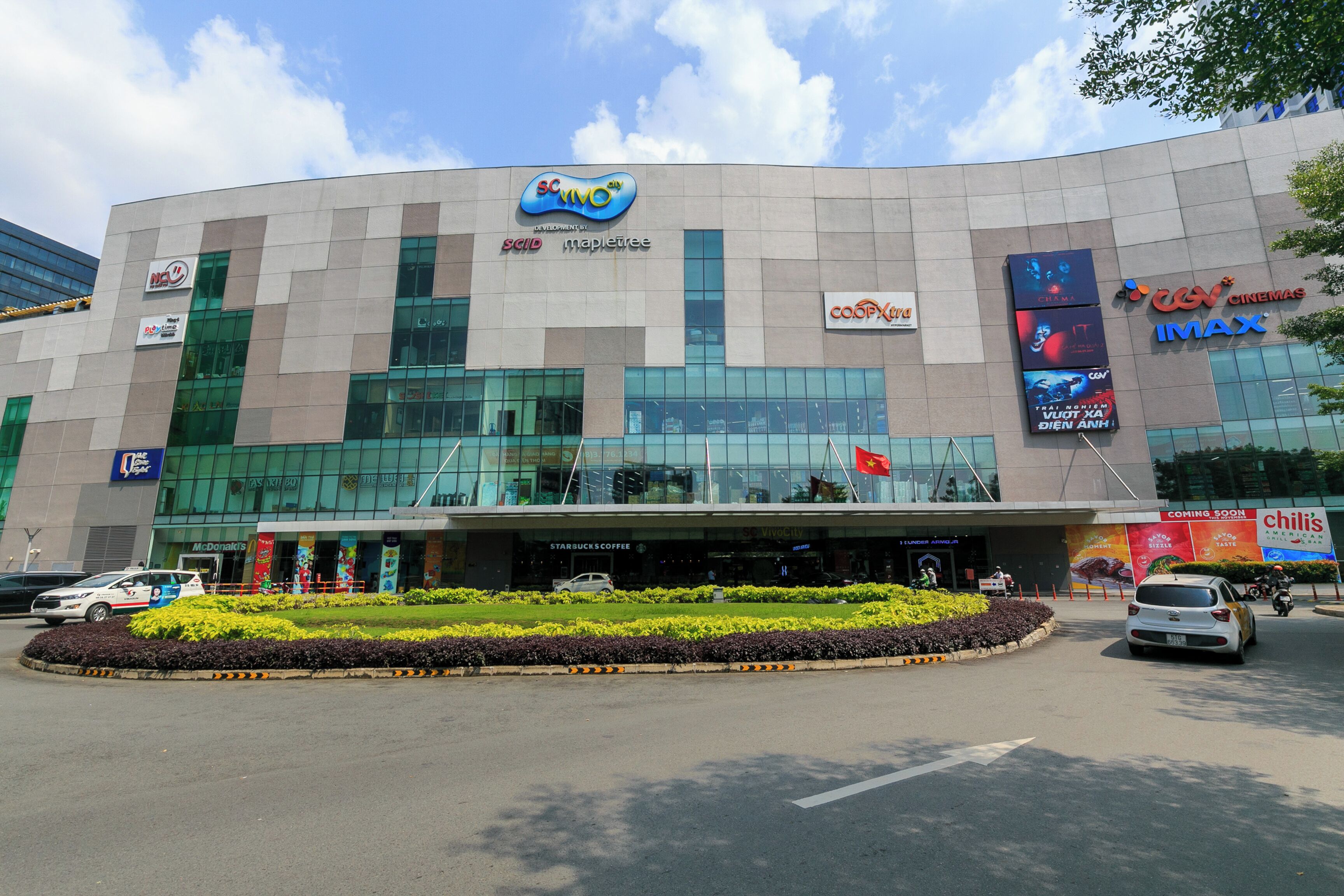 En moderne bygning med en stor glasfacade, der viser logoer for SCVIMO, mapletree og IMAX biografer.