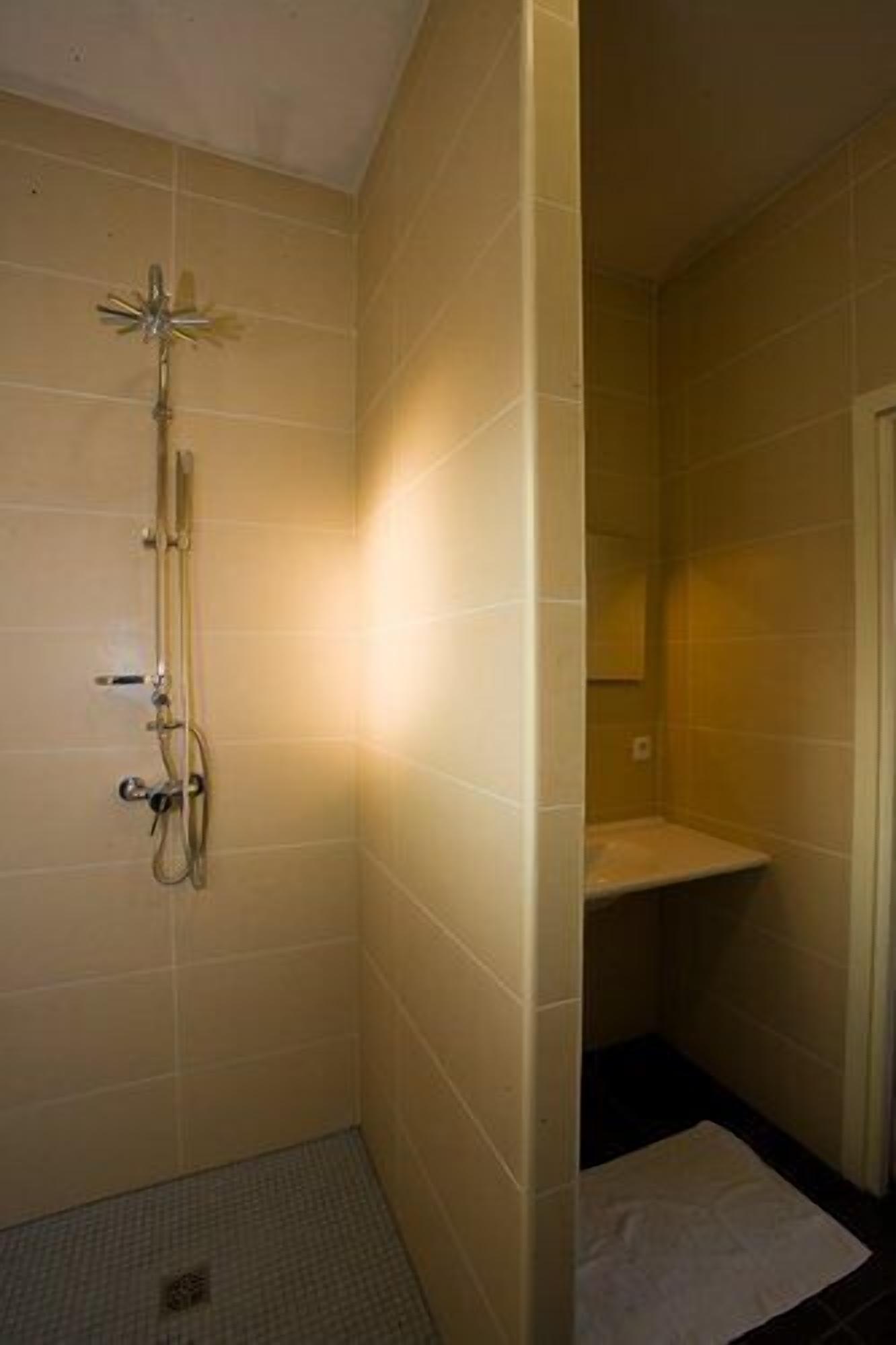 A small, tiled bathroom with a shower, a toilet, and a sink.