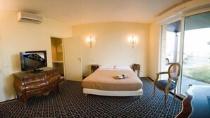Een hotelkamer met een bed, een televisie, een dressoir en een stoel.