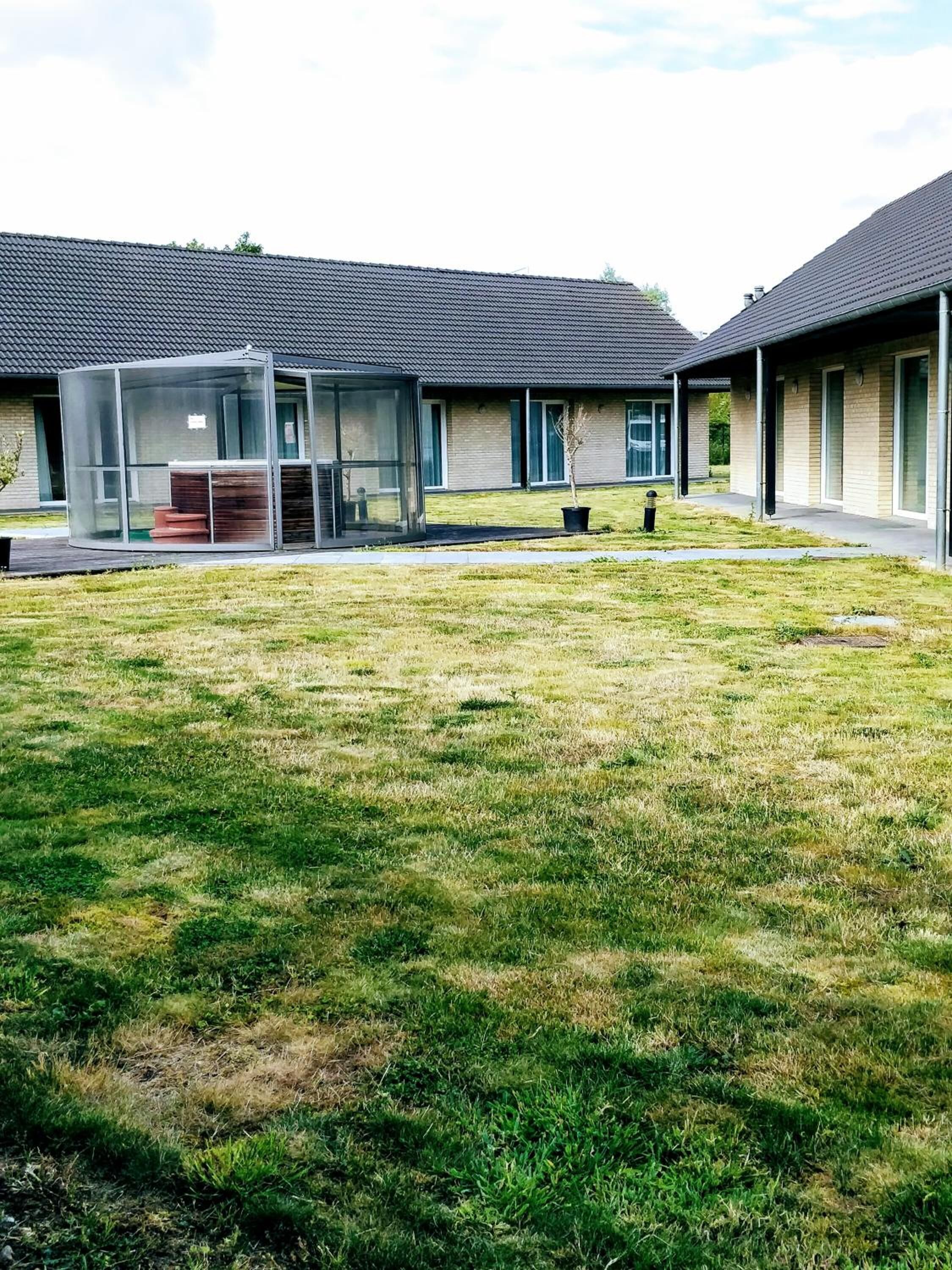 Een modern gebouw met een overdekt terras en een gazon.