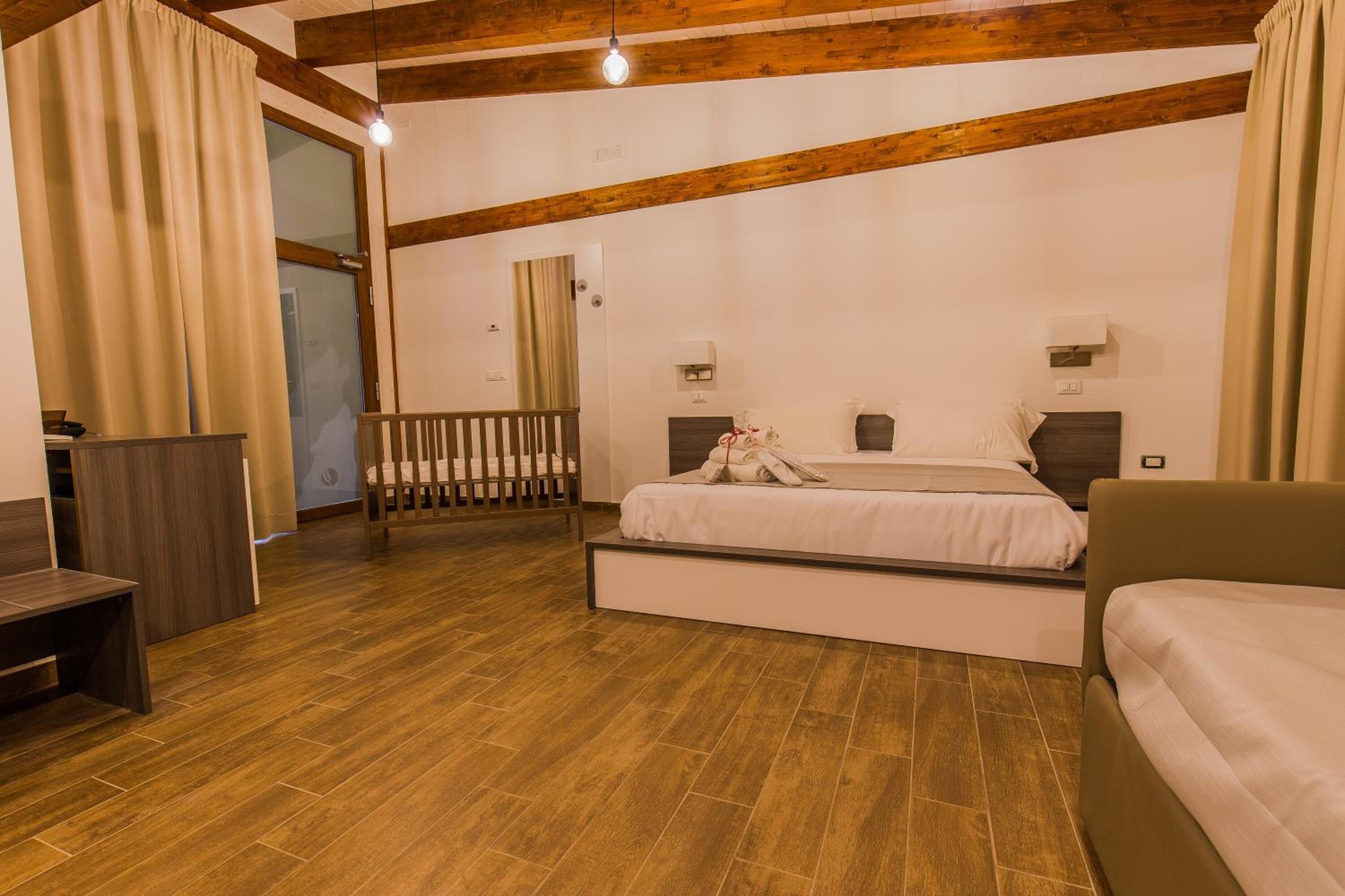 Un dormitorio con suelo de madera, cama con ropa blanca, mesita de noche, escritorio y una silla.