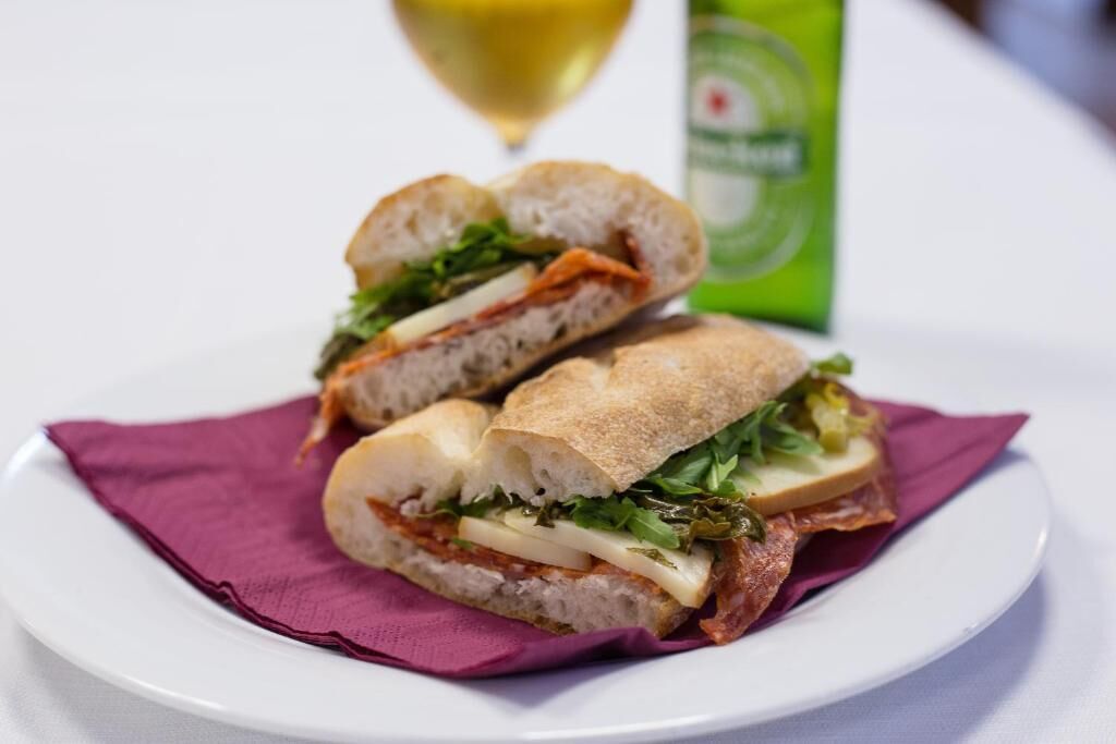 A sandwich on a plate with a bottle in the background.