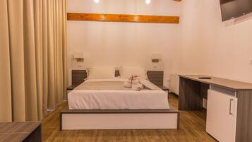 A modern hotel room with a bed, bedside tables, a desk, and a built-in wardrobe.