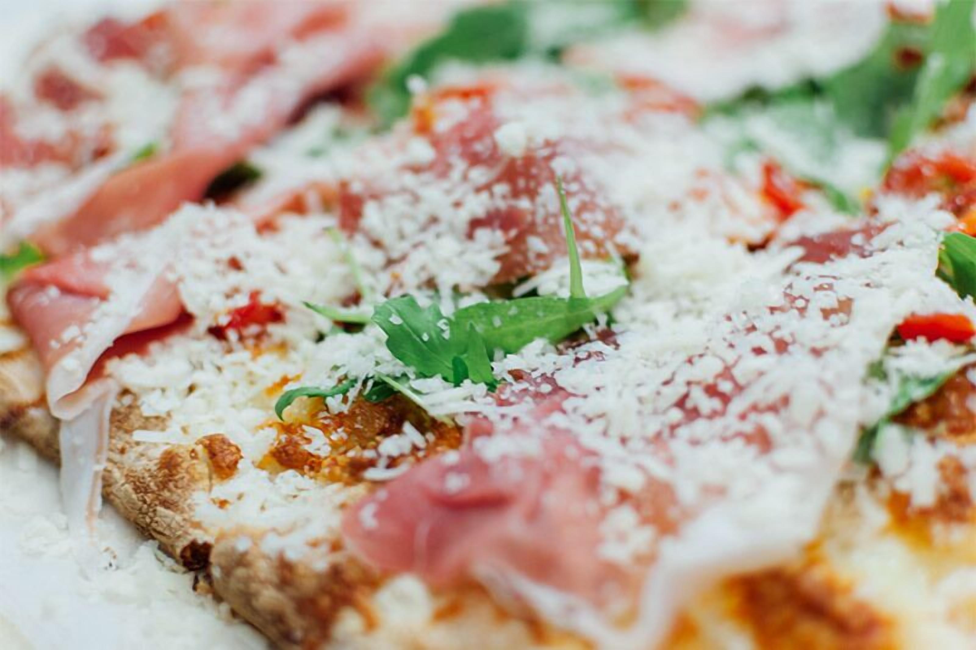 Egy pizzáról készült közeli felvétel, amelyen a feltétek is láthatók.