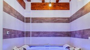 Une salle de bain moderne avec un plafond en bois, une baignoire sur pieds et un mur recouvert de carreaux.