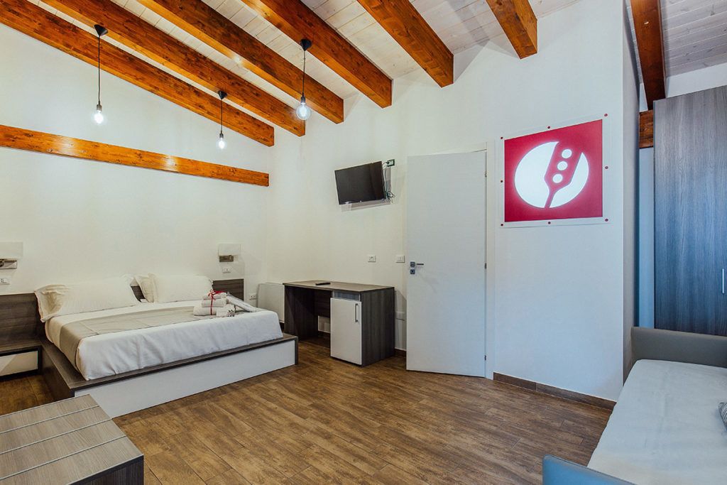 Een moderne kamer met een bed, bureau en kitchenette.