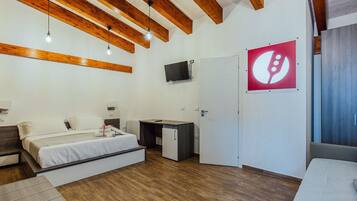 Een moderne kamer met een bed, bureau en kitchenette.