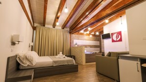 Une chambre d’hôtel moderne avec un plafond en bois, un lit, un canapé, une télévision et une kitchenette.