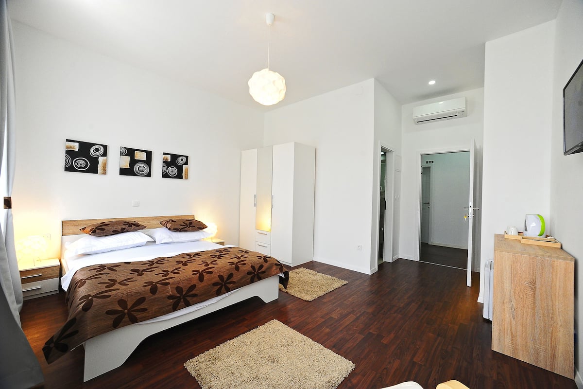 A bedroom with a bed, bedside tables, a wardrobe, a mirror, and a ceiling light.