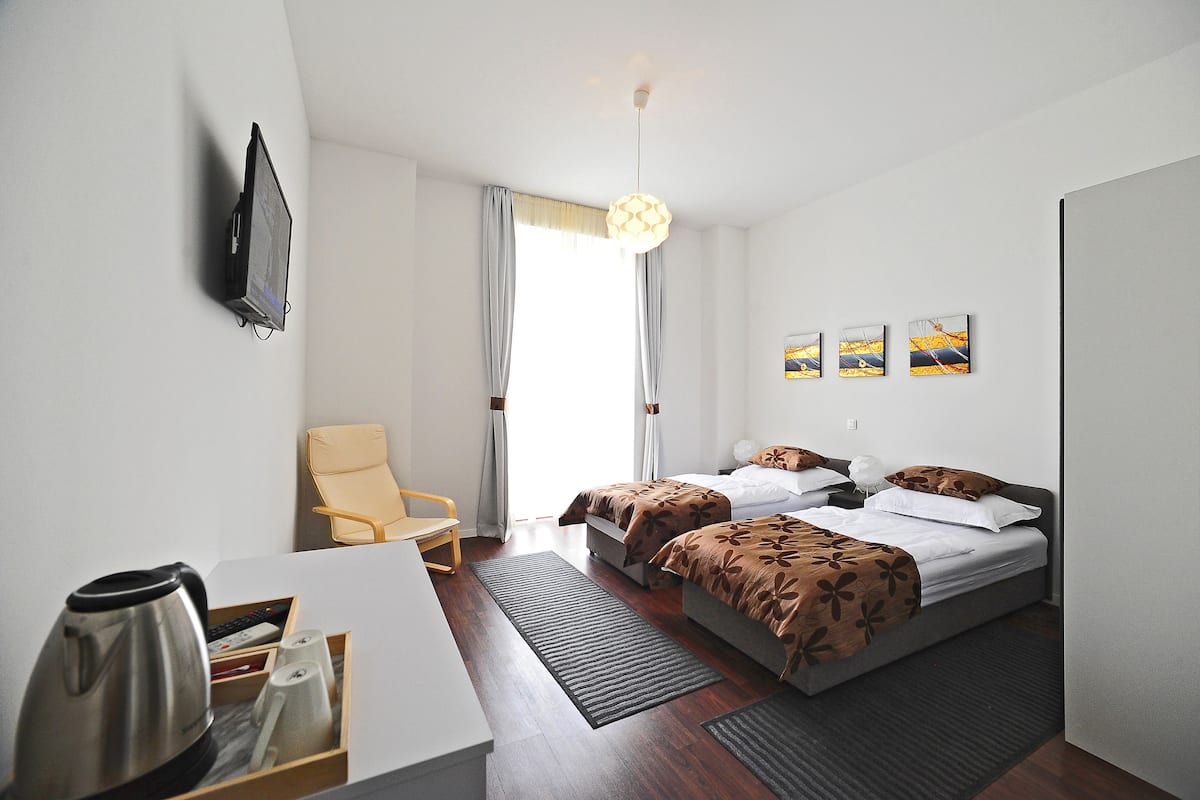 A hotel room with two beds, a desk, a chair, and a coffee maker.