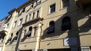 Un immeuble à plusieurs étages, doté de fenêtres en arc de cercle et d’une plaque commémorative sur la façade.