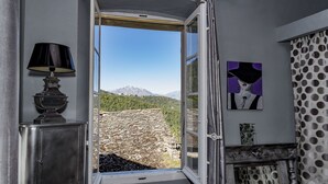 An open doorway leading to a stone terrace with a mountain view. - Chambre D'Hôtes La Marlotte (Castello-di-Rostino)