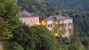 Two rustic buildings with visible windows and a forested hillside in the background. - Chambre D'Hôtes La Marlotte (Castello-di-Rostino)