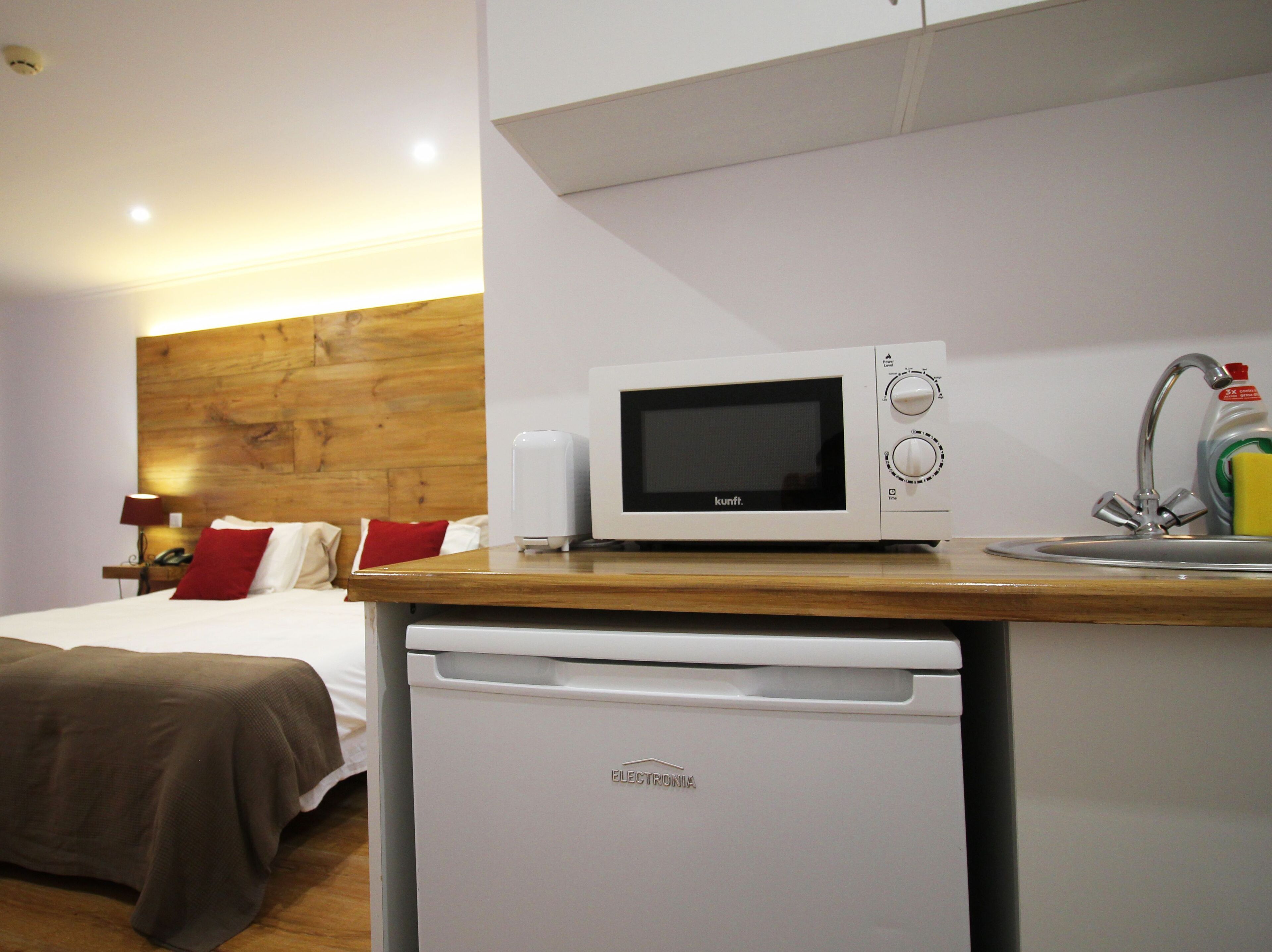 A compact kitchenette with a microwave, a small refrigerator, and a sink.