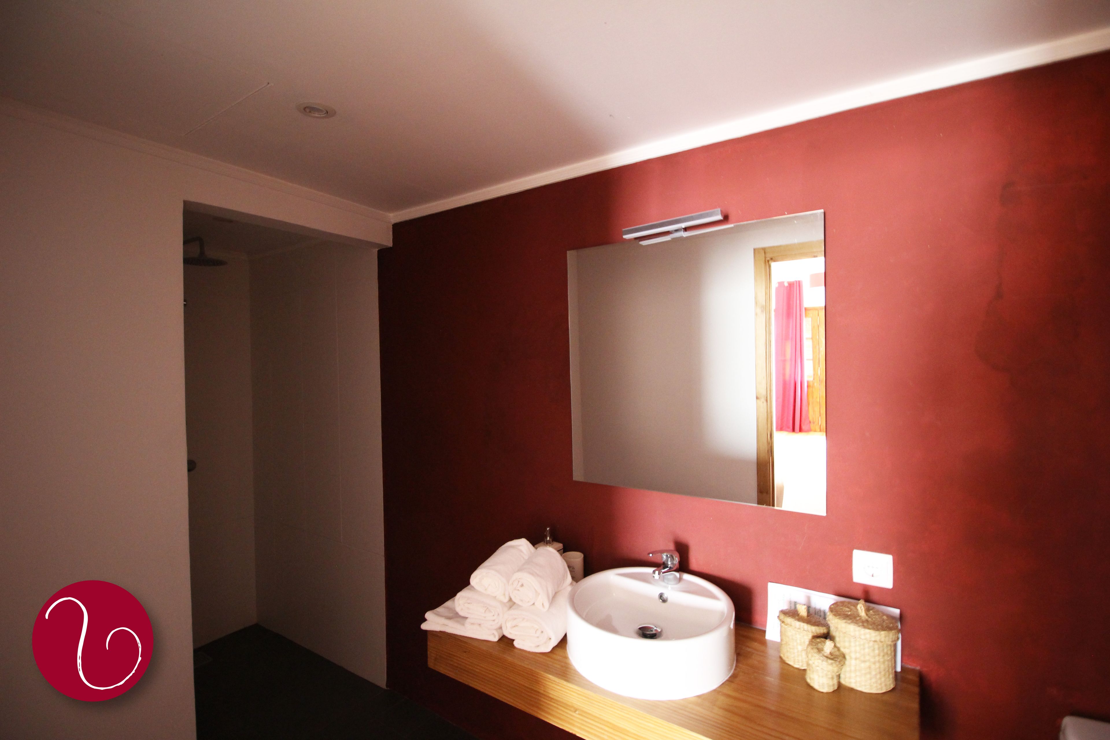A bathroom with a wooden vanity, a white sink, and a mirror.