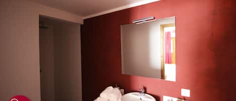 A bathroom with a wooden vanity, a white sink, and a mirror.