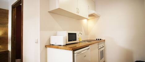 A compact kitchen with white cabinets, a microwave, a toaster, a sink, and a dishwasher.