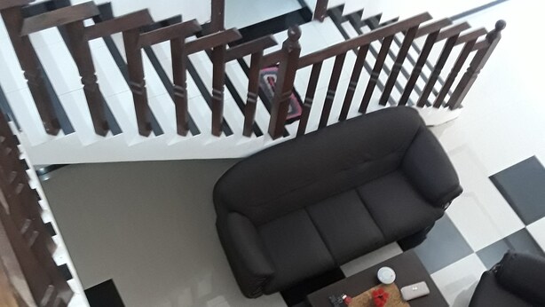 A modern living room with a black sofa set, a coffee table, and a staircase with wooden railings. - Darshani Hikka Villa (Hikkaduwa)