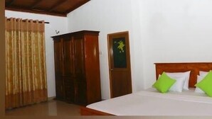 A bedroom with a bed, a wardrobe, and a door with a window. - Darshani Hikka Villa (Hikkaduwa)
