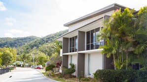 A modern building with large windows, surrounded by greenery and a hilly landscape. - 1 Bright Point Apartment 5102 (Nelly Bay)