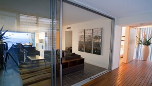 A modern living room with a glass sliding door leading to a balcony, a sofa, and a coffee table. - 1 Bright Point Apartment 5201 (Nelly Bay)