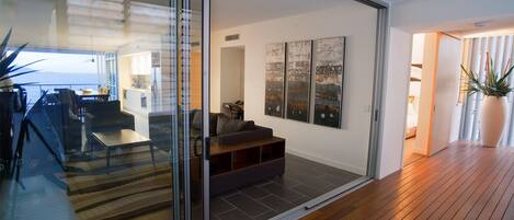 A modern living room with a glass sliding door leading to a balcony, a sofa, and a coffee table.