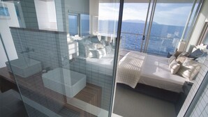 A balcony with a bed and seating area, a glass partition, and a view of the sea. - 1 Bright Point Apartment 5201 (Nelly Bay)