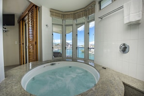 Ein Badezimmer mit einer großen Badewanne, Meerblick und einer Holztür.