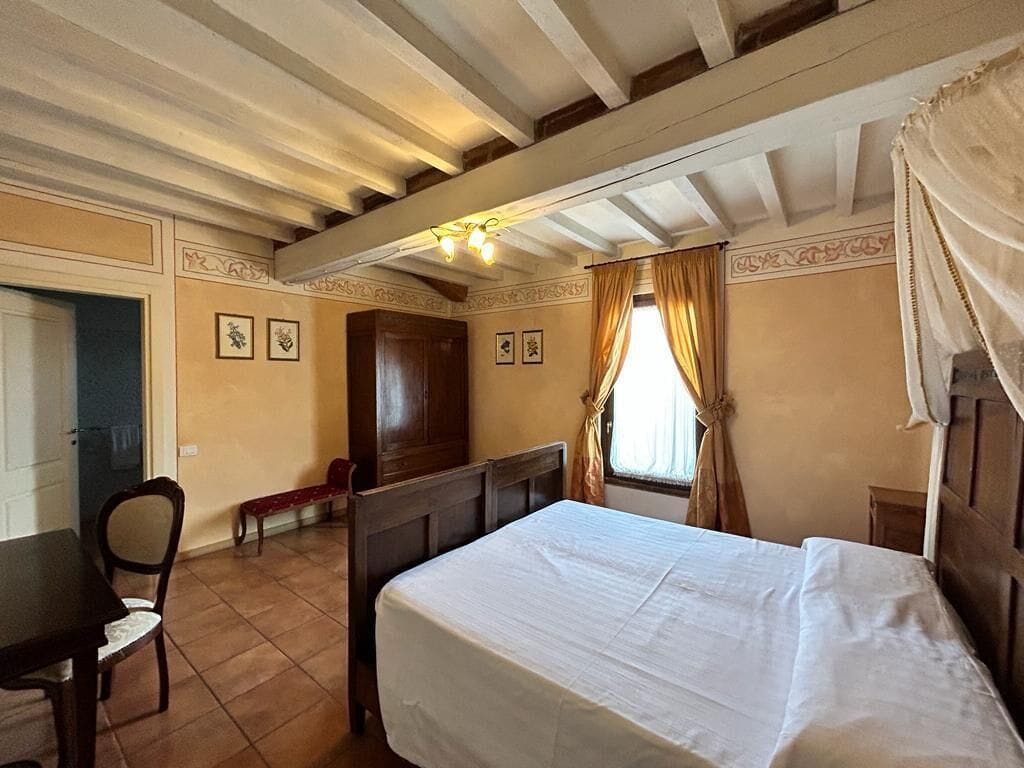 A bedroom with a bed, a wooden desk, and a chair.