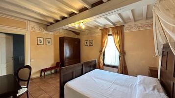 A bedroom with a bed, a wooden desk, and a chair.