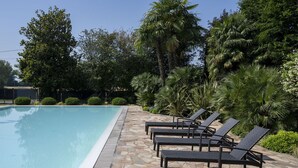 Una piscina con sillas de descanso y suelo de piedra.