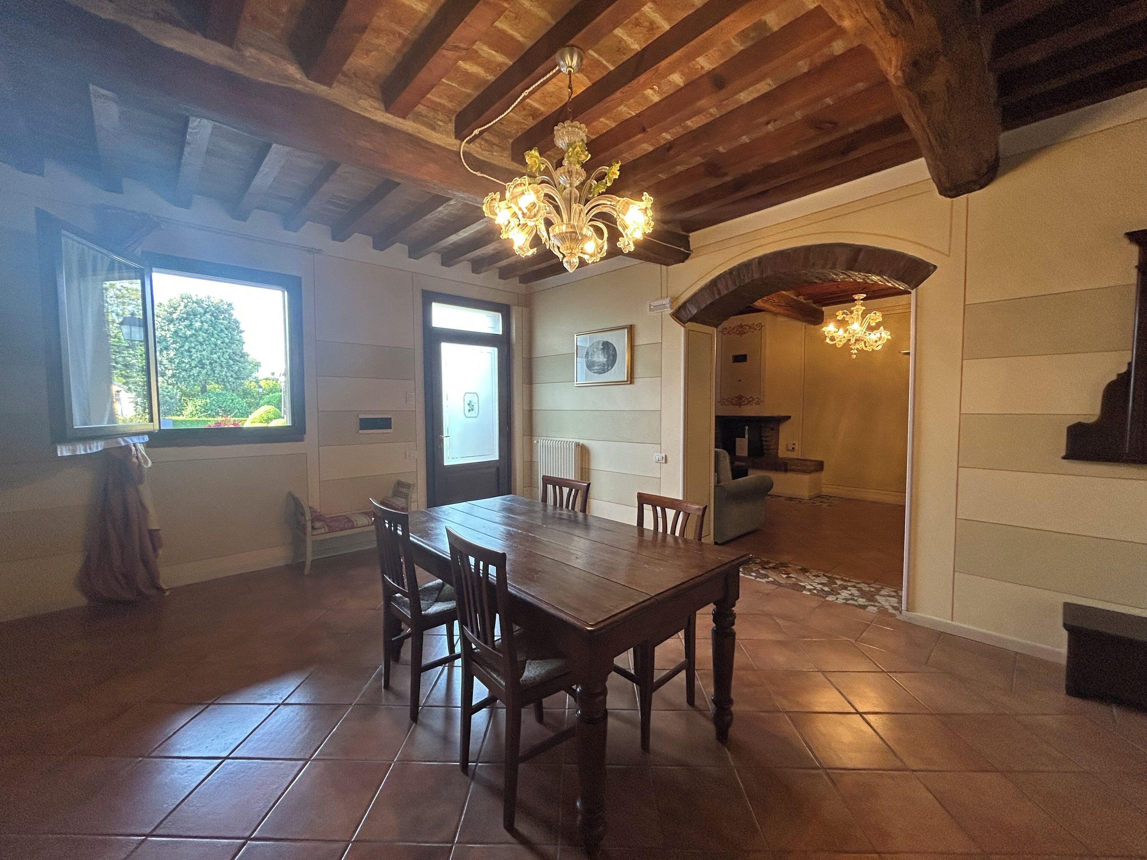 Un coin repas avec une table et des chaises en bois, un lustre et une cheminée.