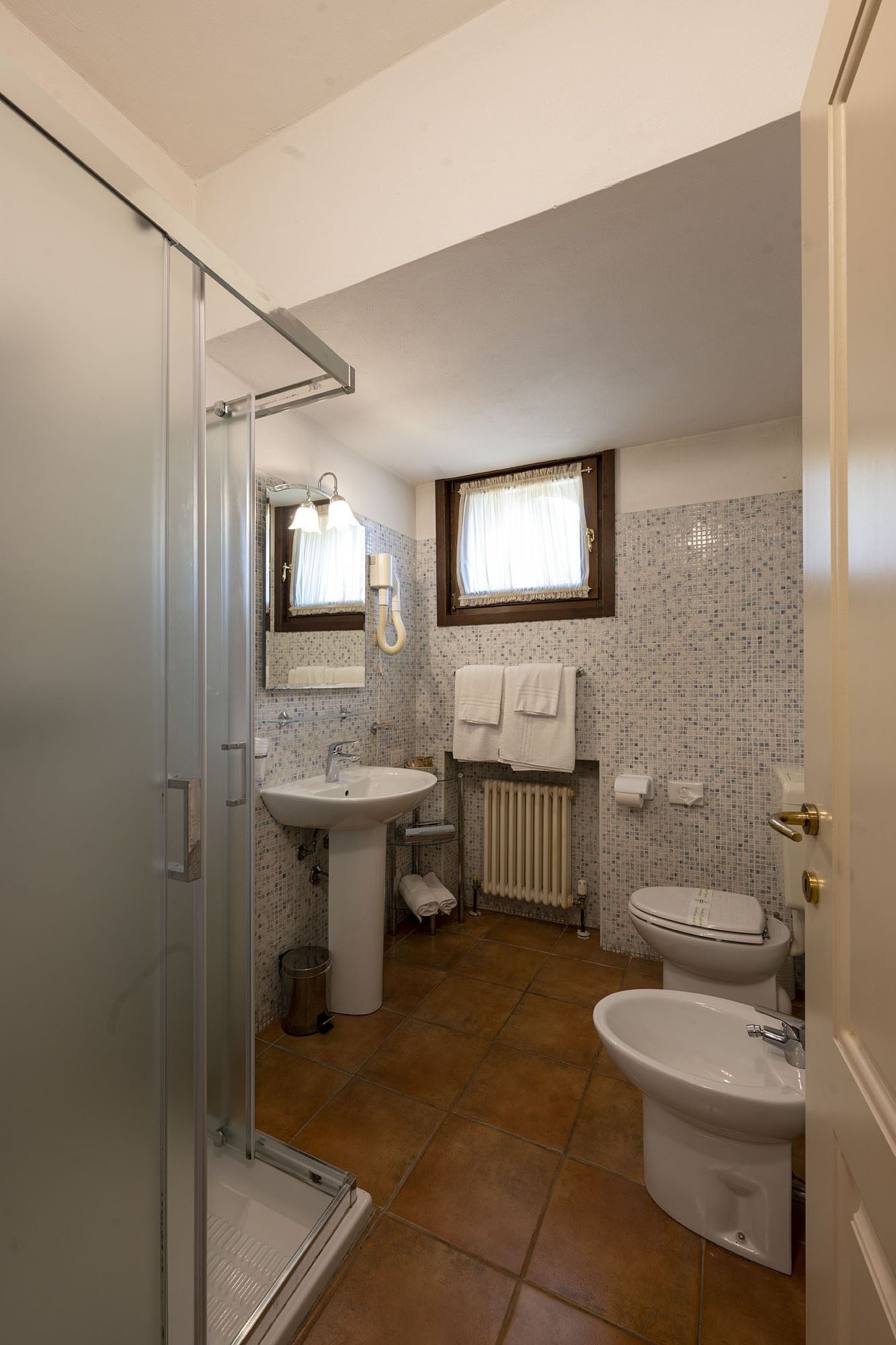 Un bagno piccolo ma funzionale con doccia, lavandino, water e bidet.