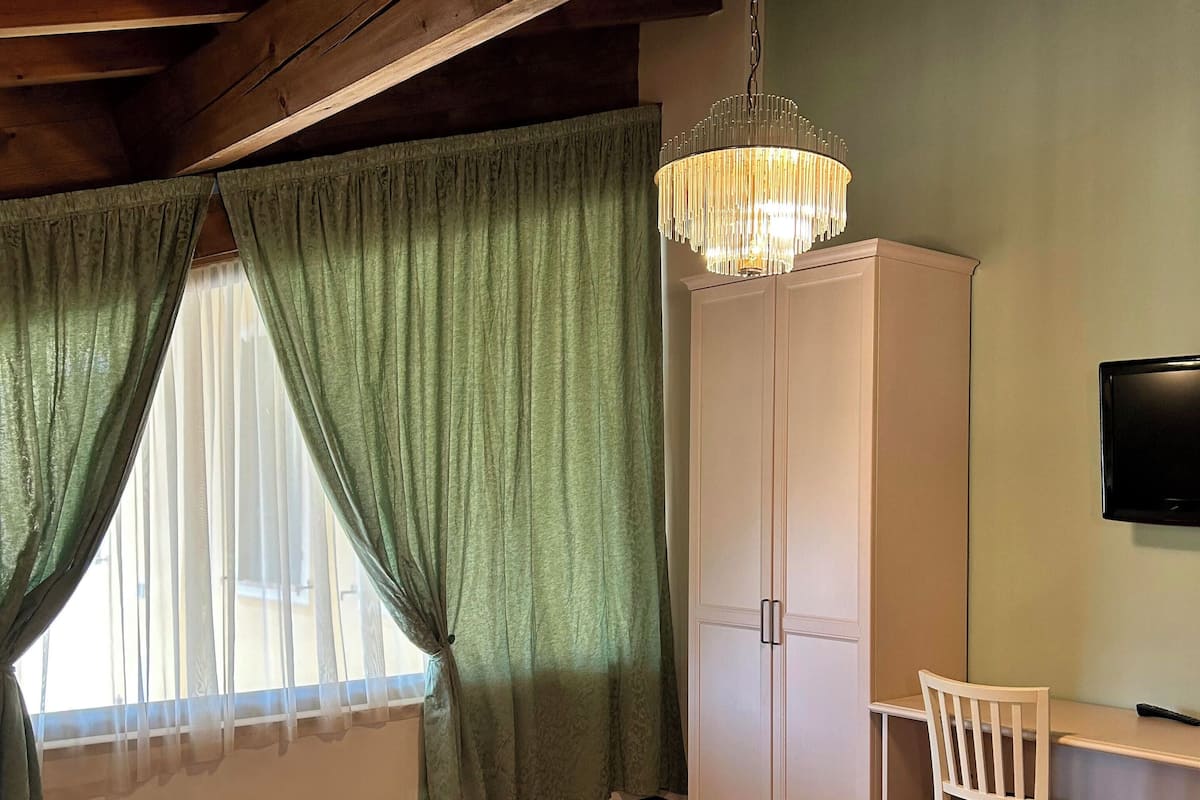 A bedroom with a bed, a wardrobe, a desk with a chair, and a television.